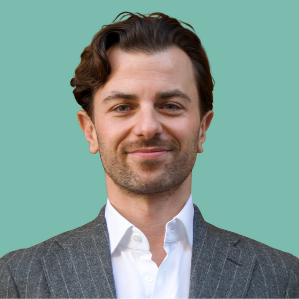 Man wearing a gray suit and white shirt against a teal background